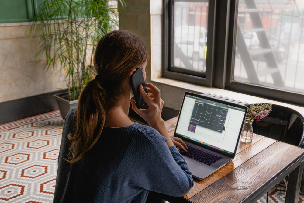 Woman on the phone typing on laptop.